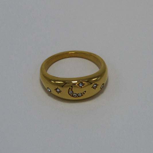 Gold ring with moon and star designs on a light gray background