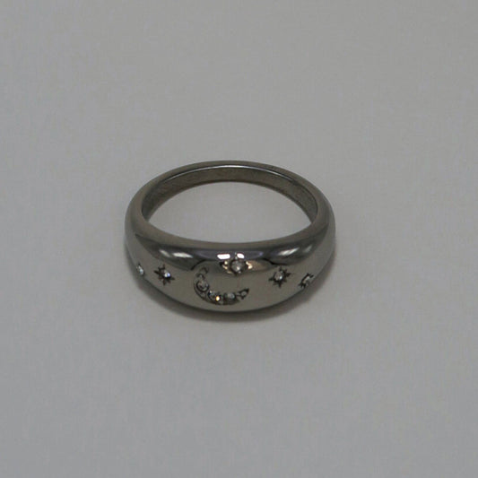 Silver ring with star and moon designs on a light gray background