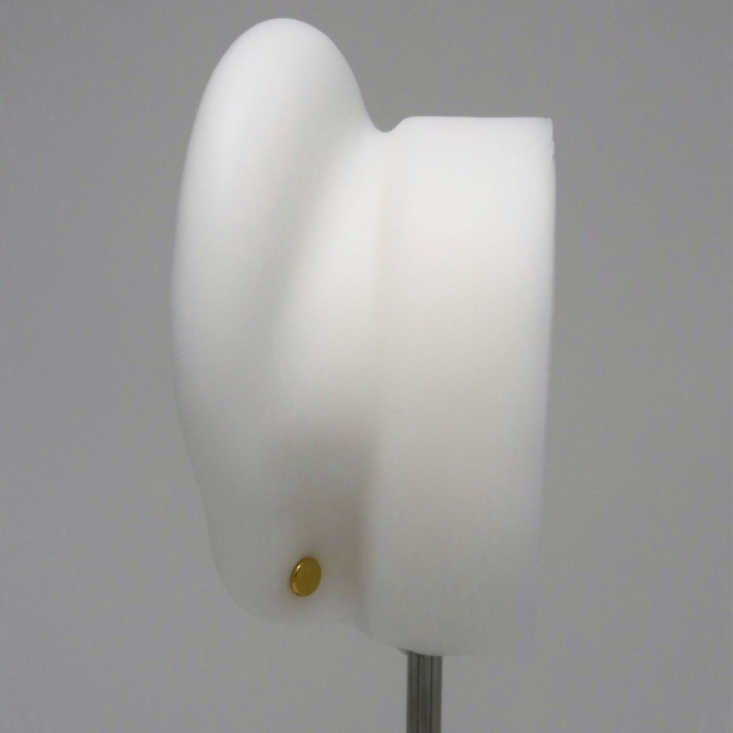 The back of a white ear model with a gold flat back earring post on a gray background