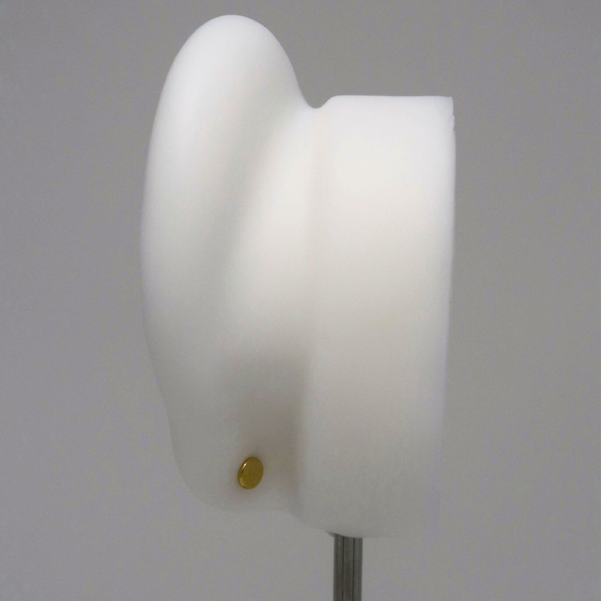 The back of a white ear model with a gold flat back earring post on a gray background