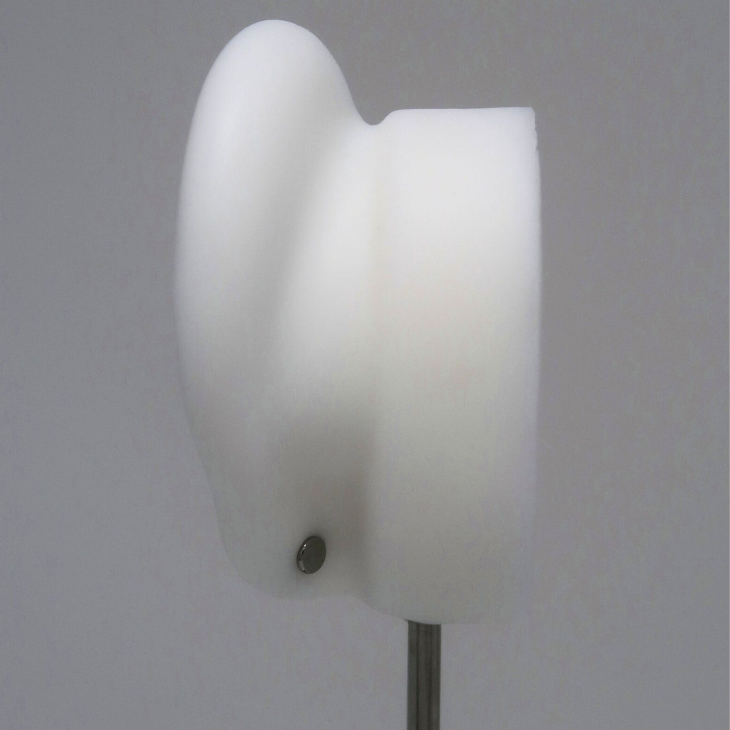 The back of a white ear model with a silver flat back earring post on a gray background