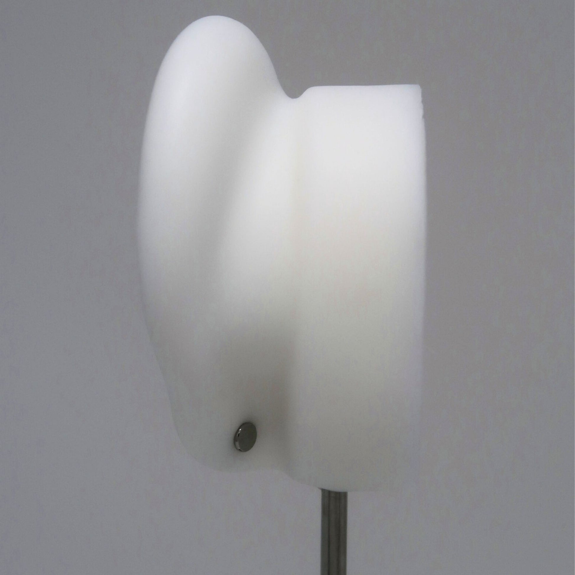 The back of a white ear model with a silver flat back earring post on a gray background