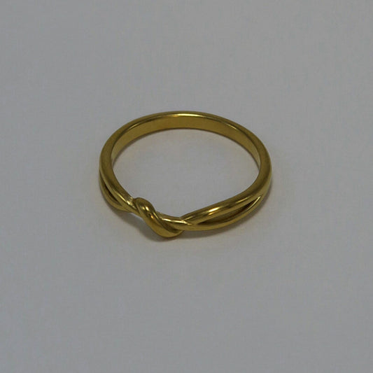 Gold ring with a twisted design on a light gray background